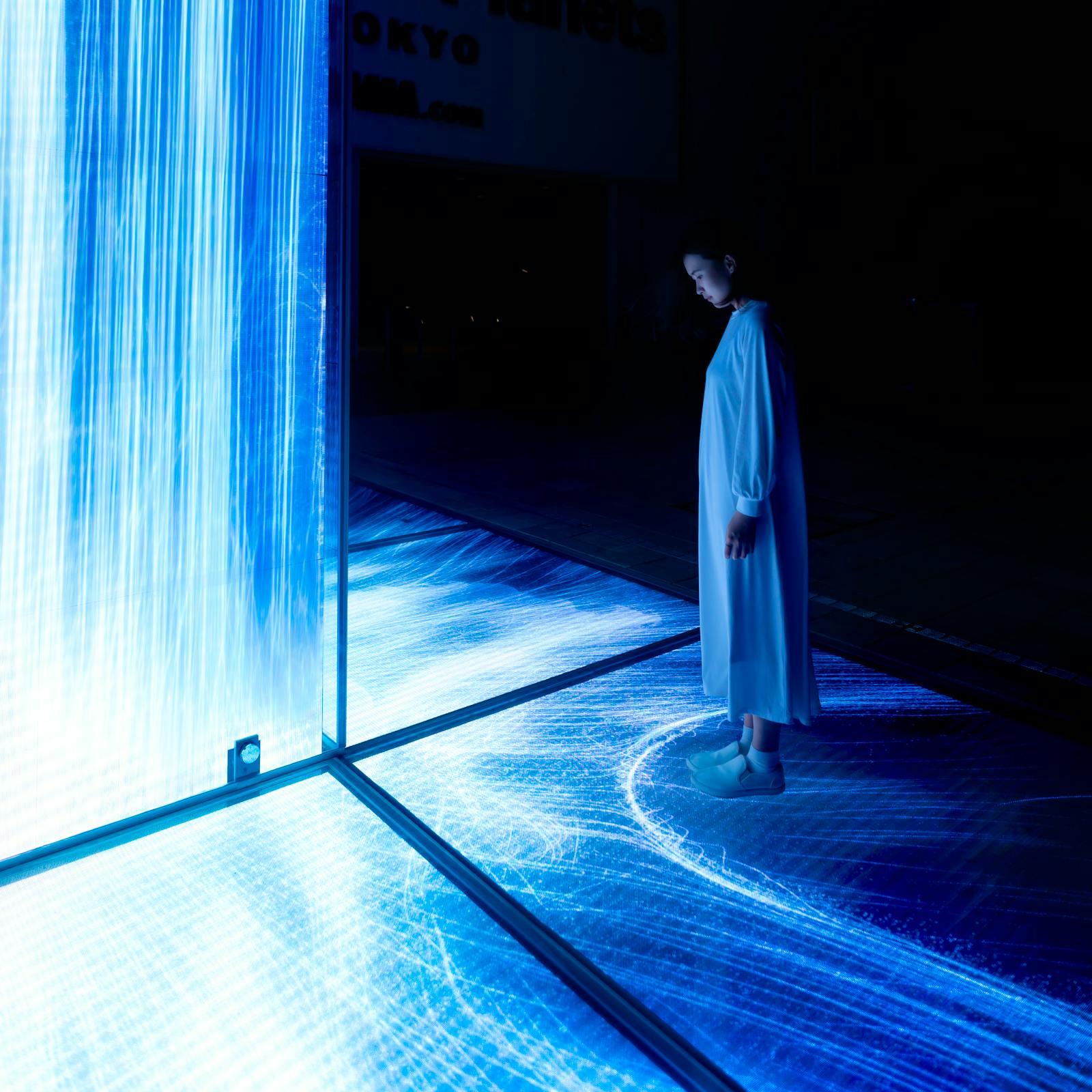 Mulher solitária diante de uma projeção luminosa no teamLab Planets